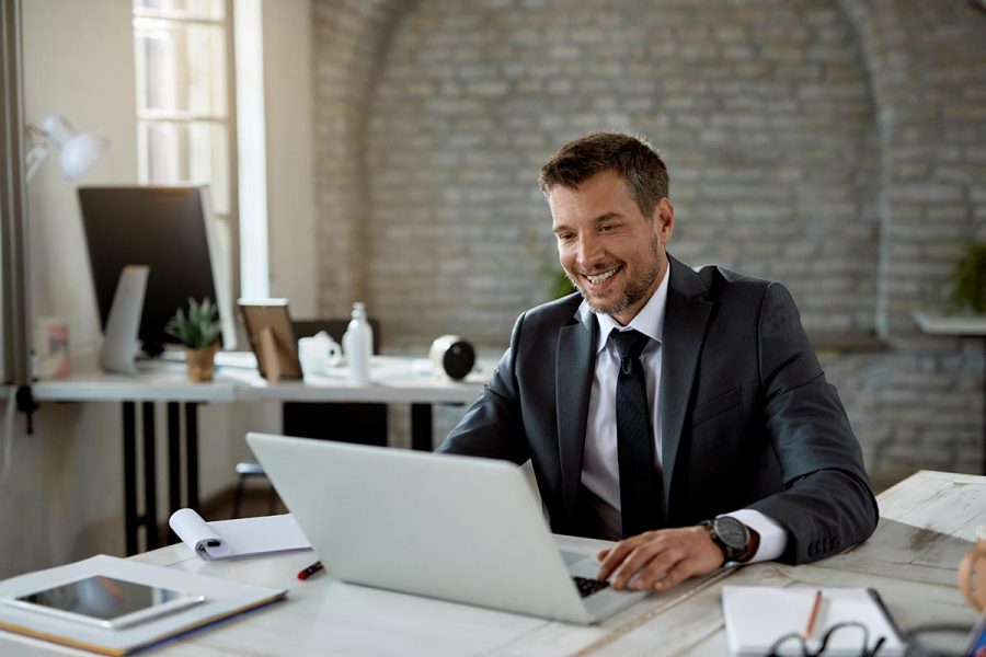 Homme expert-comptable souriant devant son ordinateur à son bureau