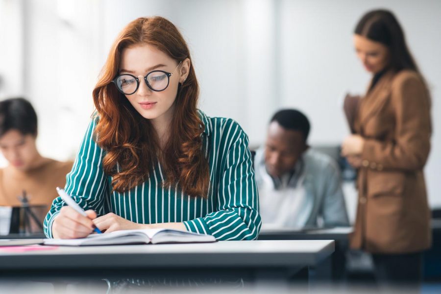Etudiante assise en classe en train de prendre des notes sur un cahier