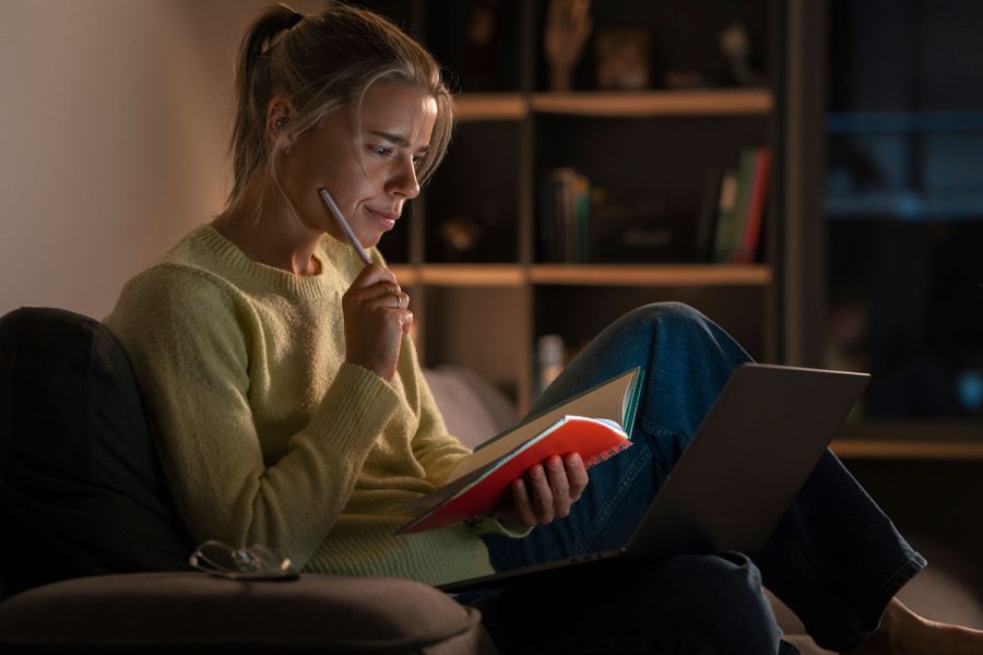 Jeune femme étudiante en train de réviser ses cours de comptabilité dcg le soir