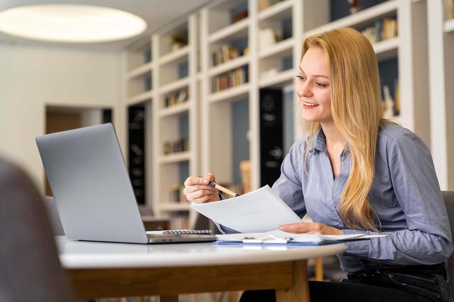 Une femme assise dans un bureau devant son ordinateur exerçant ses missions d'assistant comptable