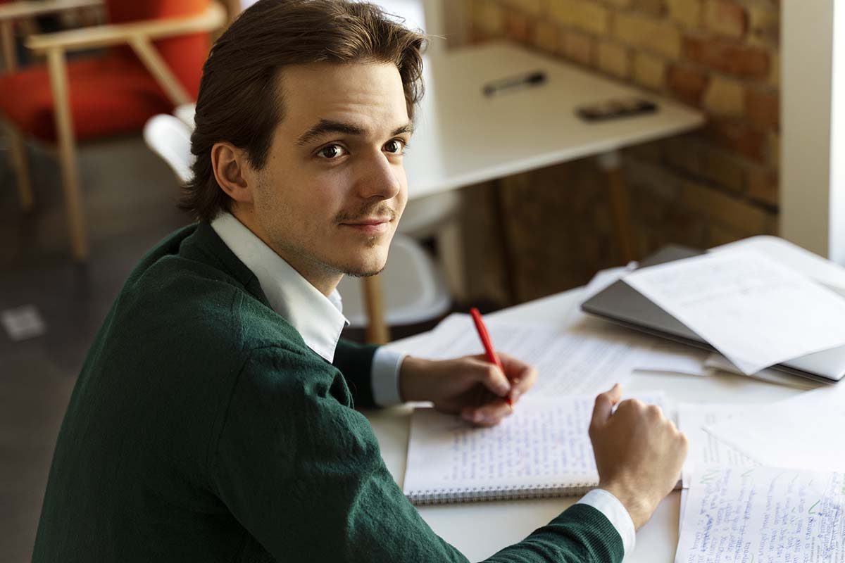 Un homme avec un stylo dans la main passe son examen tp gestionnaire comptable et fiscal avec l'ENCG.