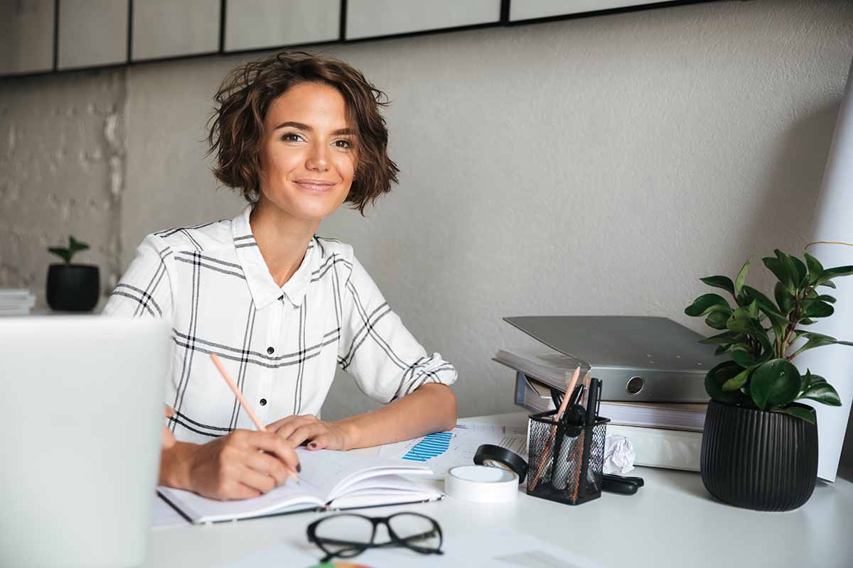 Une femme à son bureau qui suit le programme du TP Comptable Assistant.