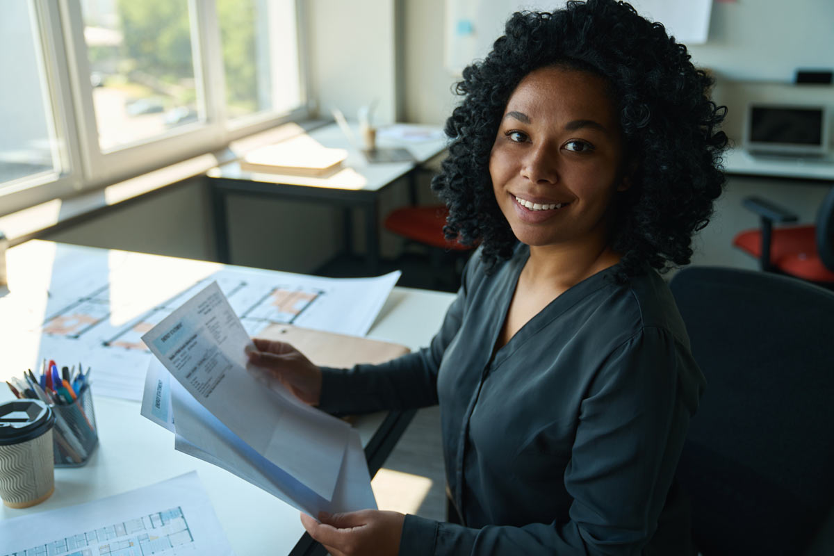 Femme gestionnaire de paie tenant un bulletin de paie après revalorisation smic janvier 2026