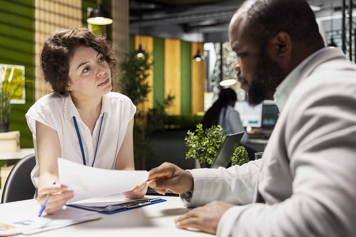 Un candidat gestionnaire de paie donne sa lettre de motivation à la femme recruteuse lors d'un entretien.