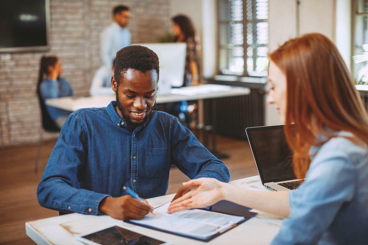 Un étudiant signant son contrat d'alternance qui connait les différences entre contrat pro et contrat d'apprentissage