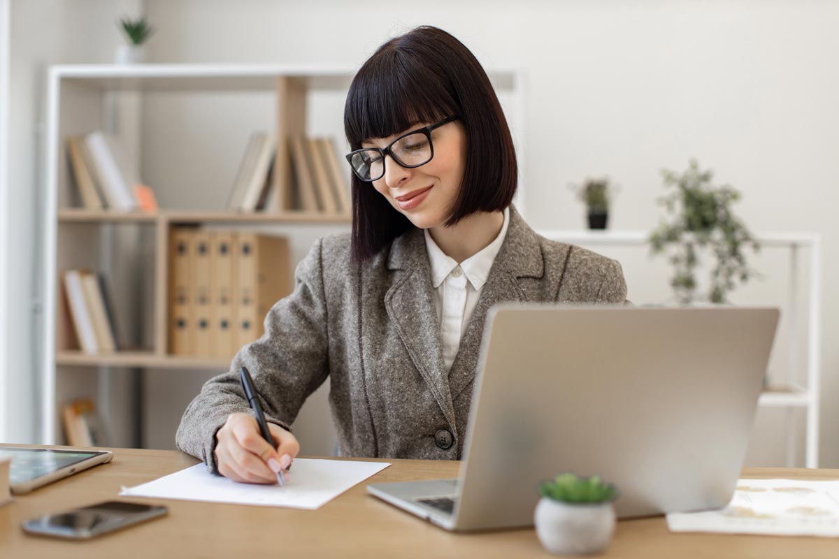 Jeune femme travaillant sur la rédaction de sa lettre de motivation comptable.