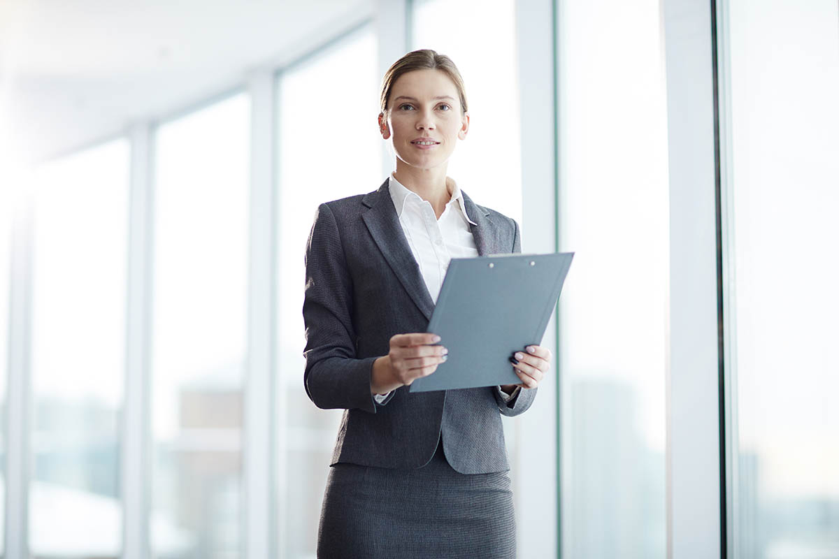 Une femme avec des documents à la main pour s'inscrire à une formation pour sa reconversion contrôleur de gestion.
